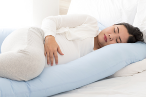 Pregnant woman uses pillow to sleep on side comfortably